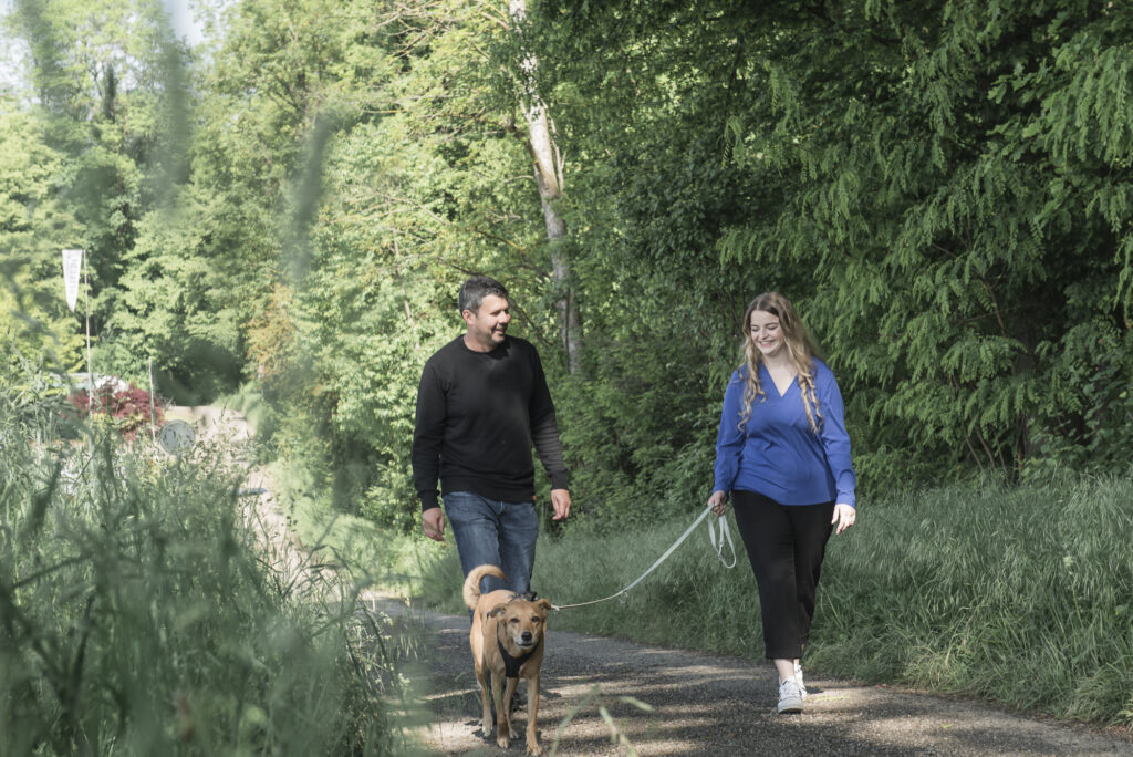 Zwei Personen lernen sich bei einem Spaziergang mit Hund kennen.