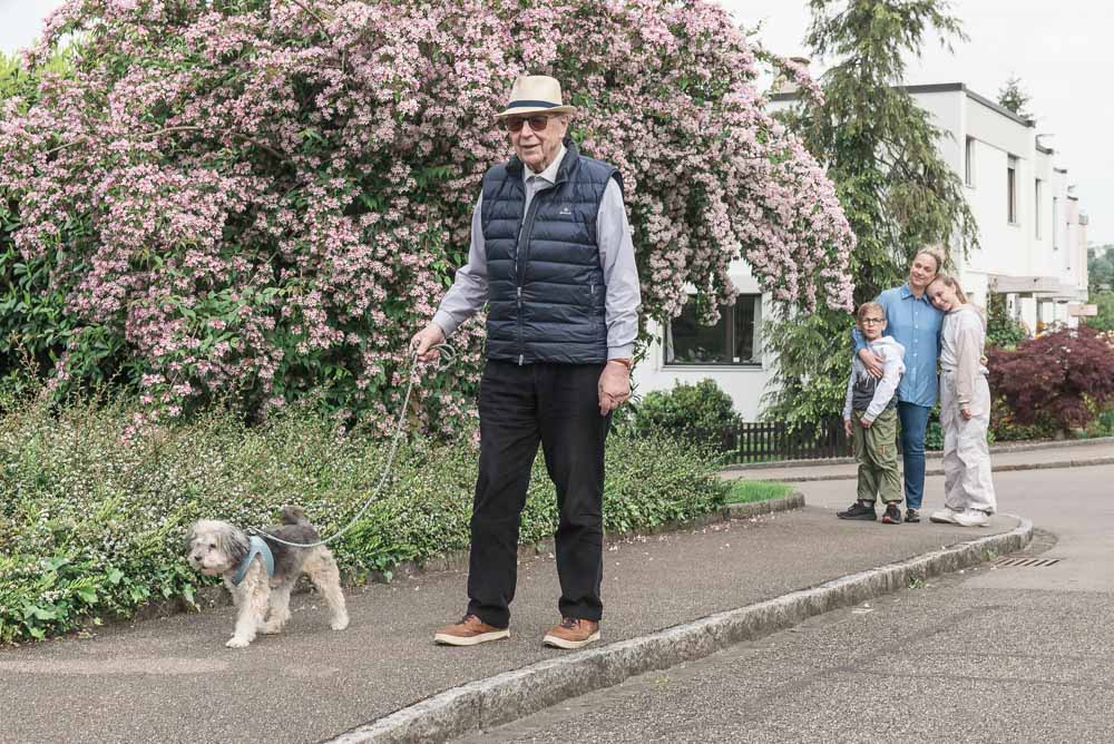 Eine junge Familie und ein Rentner betreuen einen Hund gemeinsam, damit für den Hund immer gesorgt ist. So geht es dem Hund immer gut.